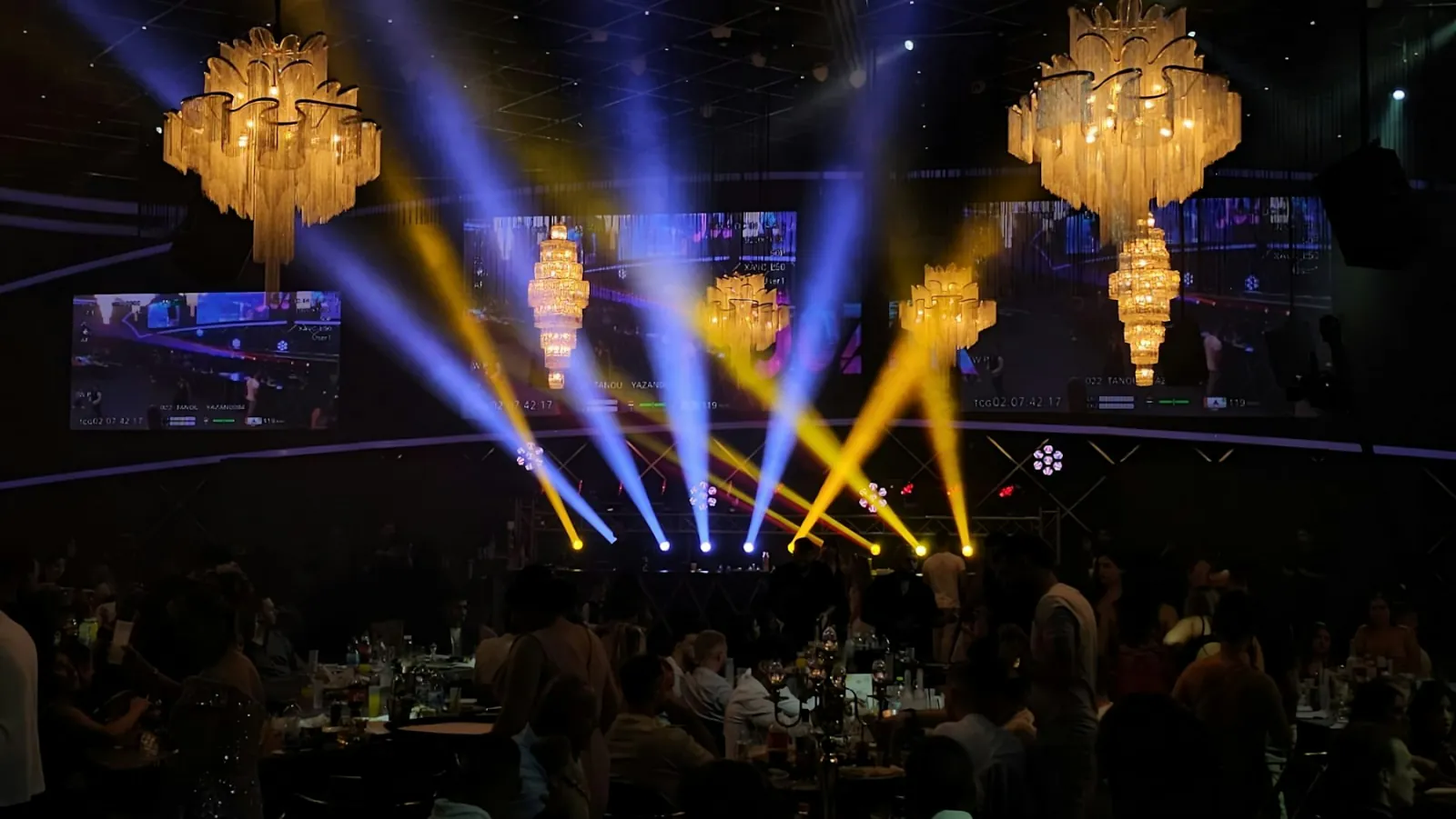 Gala ballroom with crystal chandeliers, moving-head light beams and dinner tables