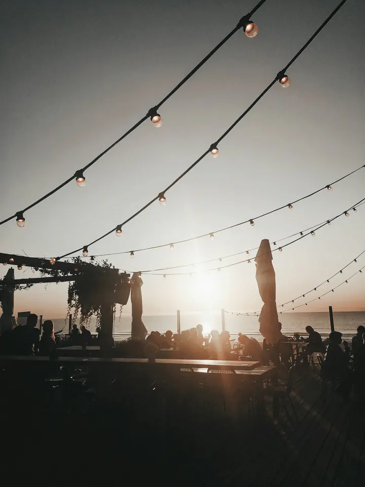 Party guests gathered under strings of lights at sunset