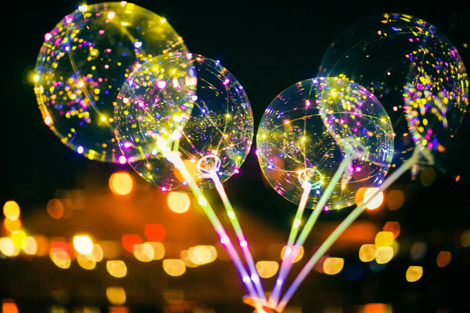 Glowing LED balloons and colourful bokeh lights at a night party